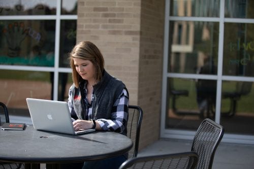 Student sitting outdoors on her computer