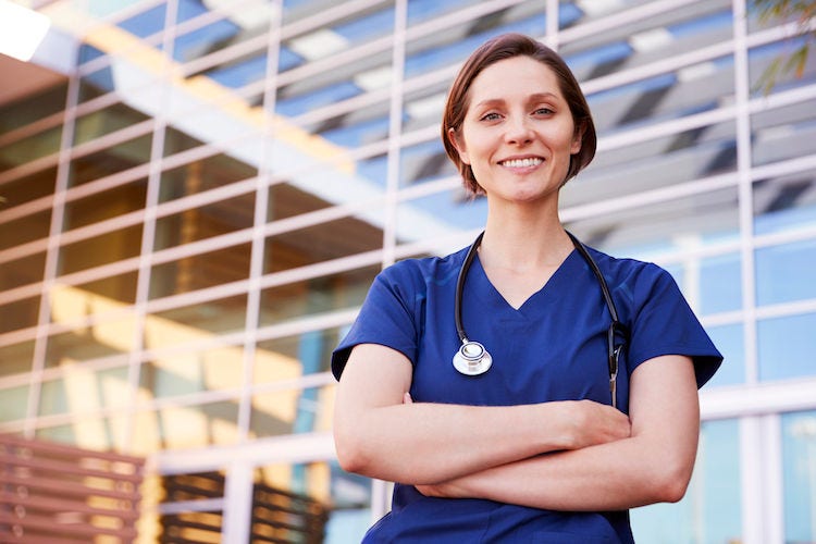 Smiling white female healthcare worker outdoors, waist up