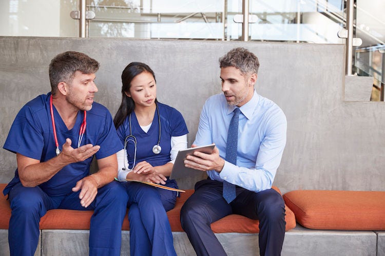 Healthcare workers in discussion using a tablet computer