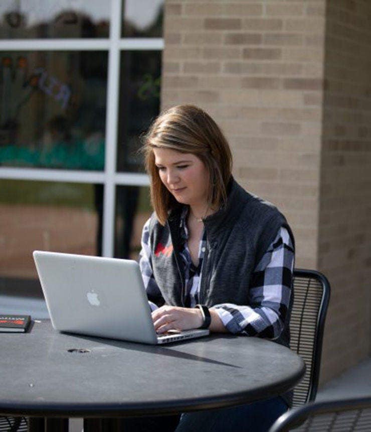 Student sitting outdoors on her computer